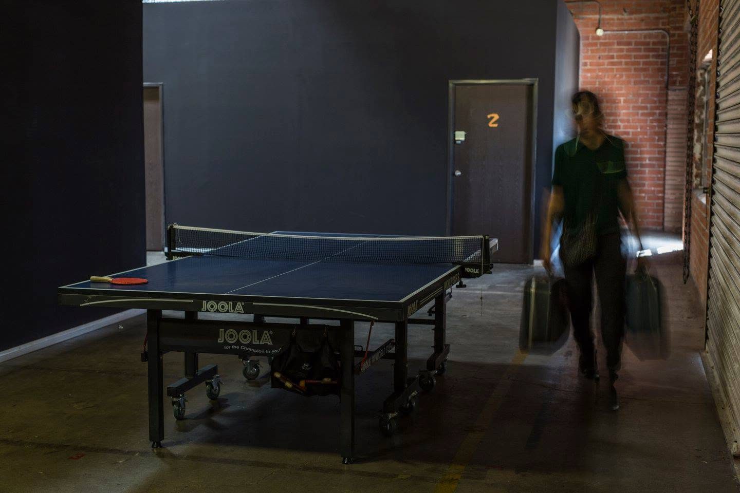 Artist carrying gear past the ping pong table toward the studios