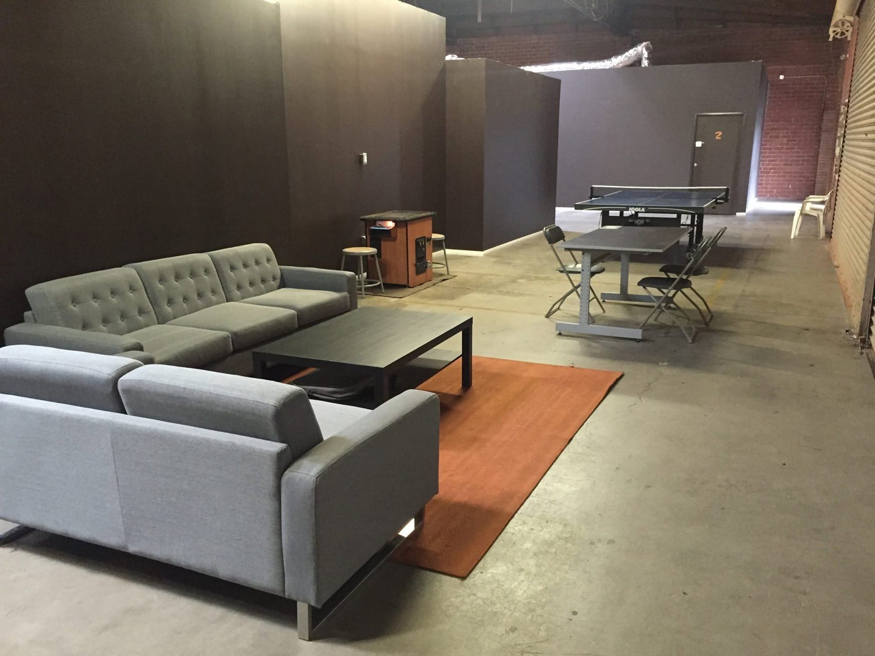 Players lounge with grey couches, coffee table and ping pong table beyond