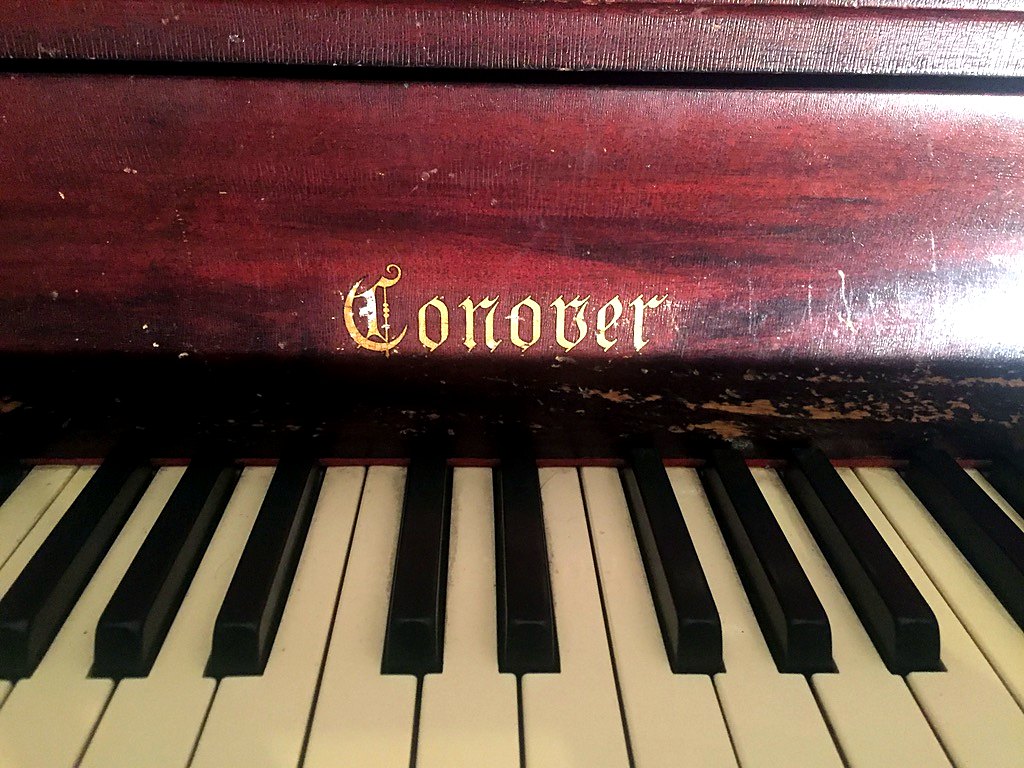 Gold Conover lettering above the keys of the vintage upright piano