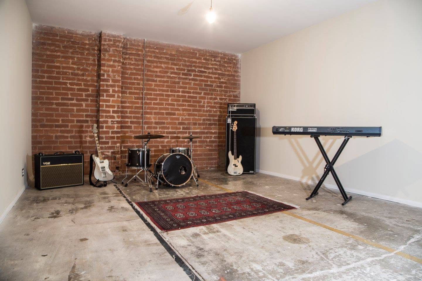 Large studio with exposed red brick wall, drum kit, amps and keyboard